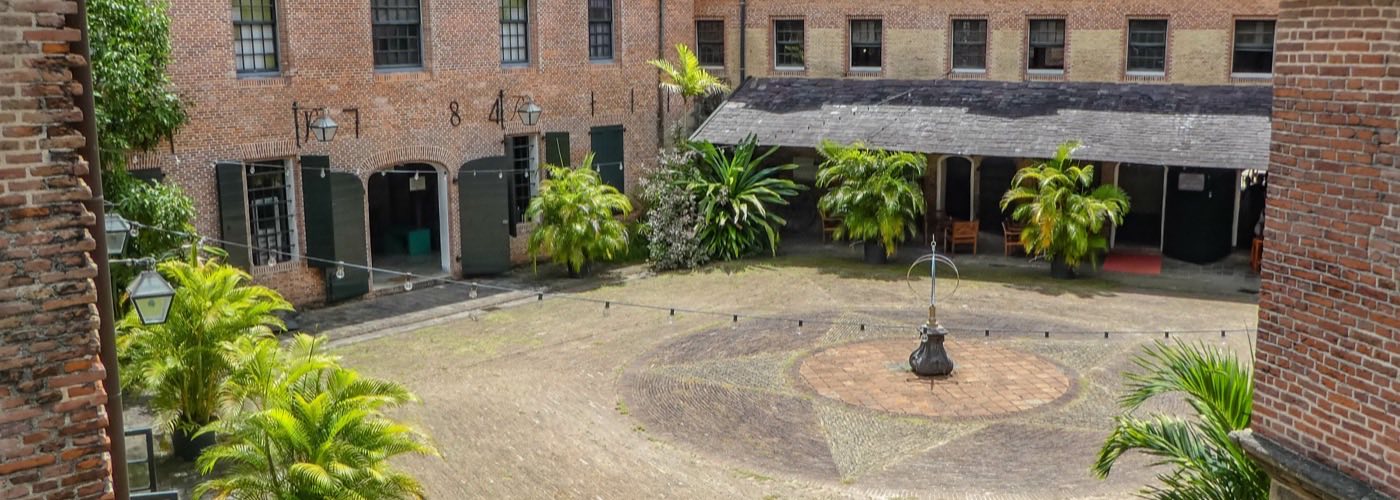 The brick inner courtyard of Fort Zeelandia in Paramaribo, ringed by two-storey colonial buildings and potted palms.