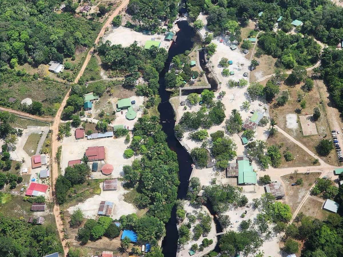 Aerial view of Colakreek recreation park, with the dark creek winding between white sand and pavilions.