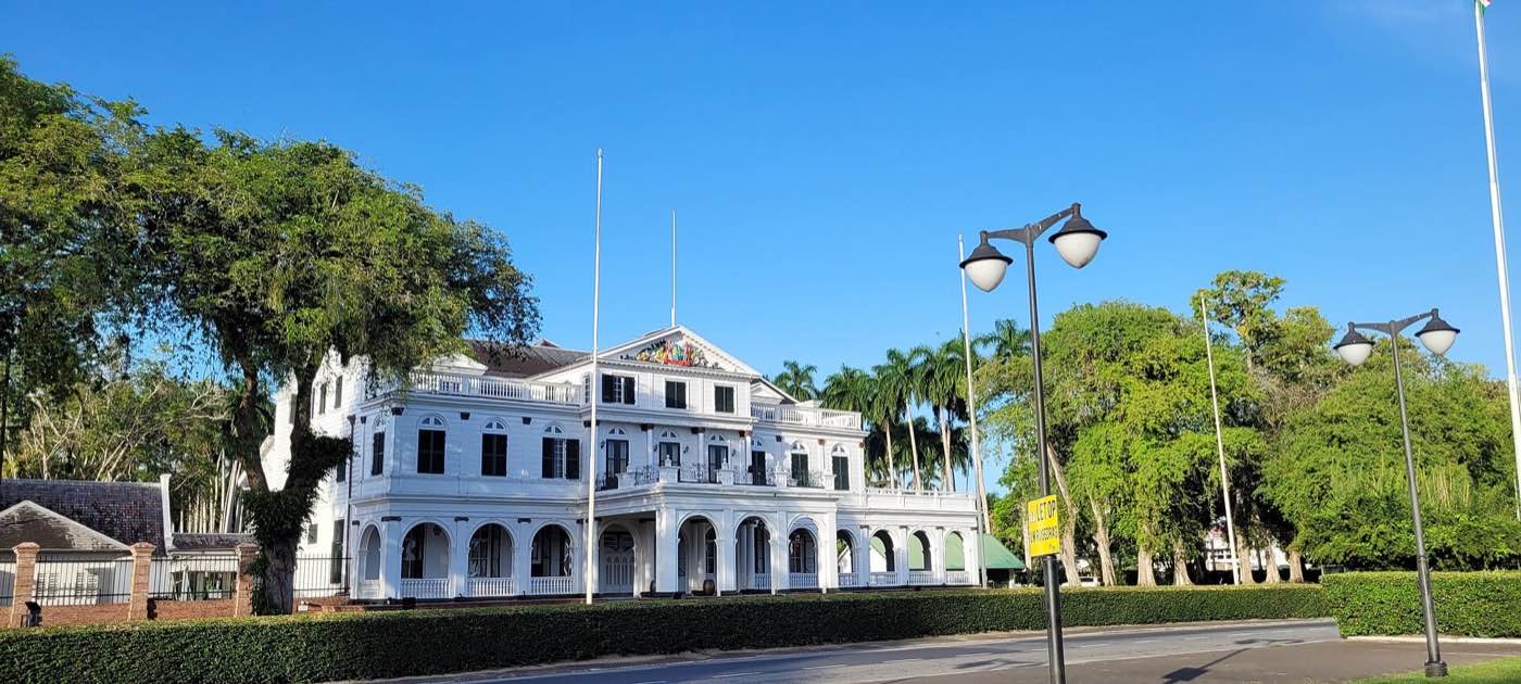 The white Presidential Palace of Suriname behind trimmed hedges on Onafhankelijkheidsplein.
